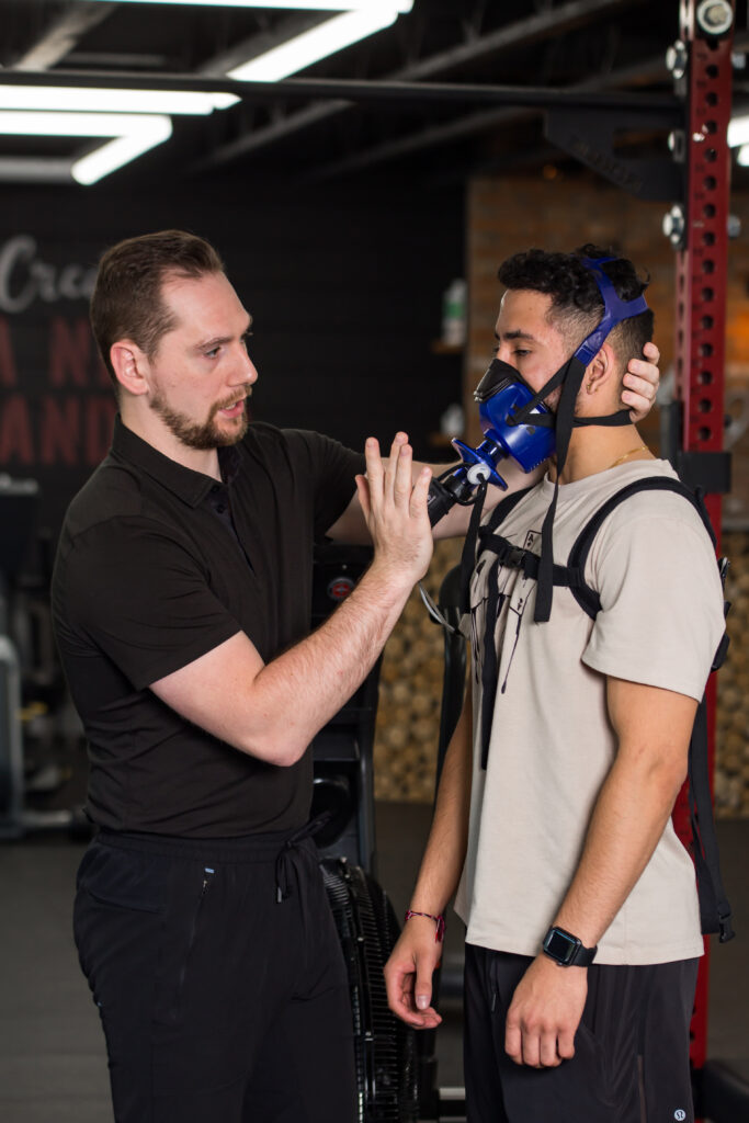 A man in a gym getting fitted with a breathing mask.