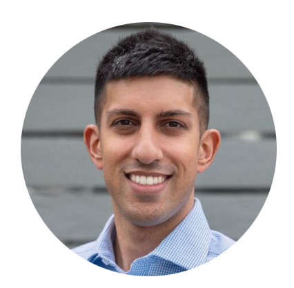 Our team member wearing a blue shirt smiling in front of a gray wall.